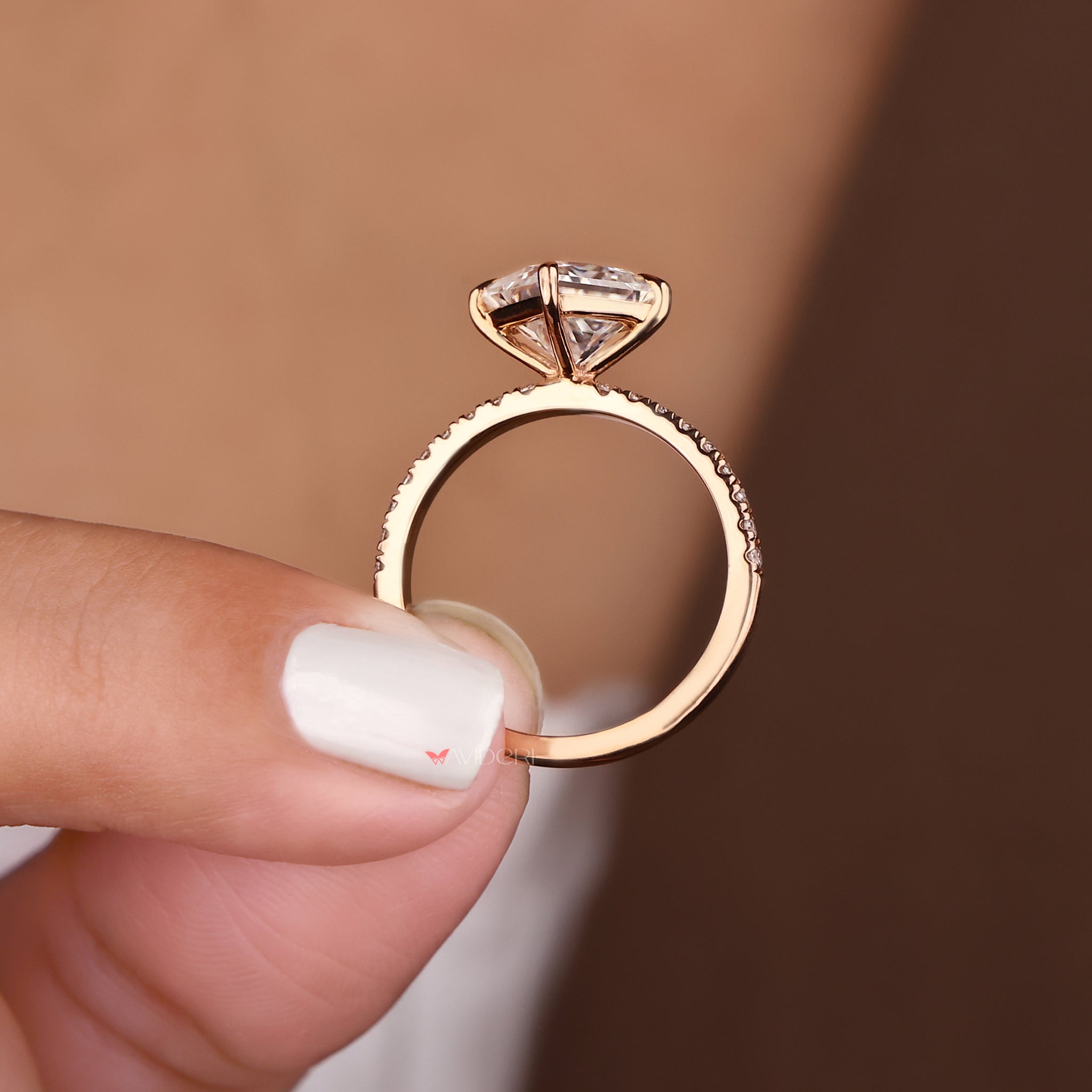 A rose gold engagement ring placed on a white surface.