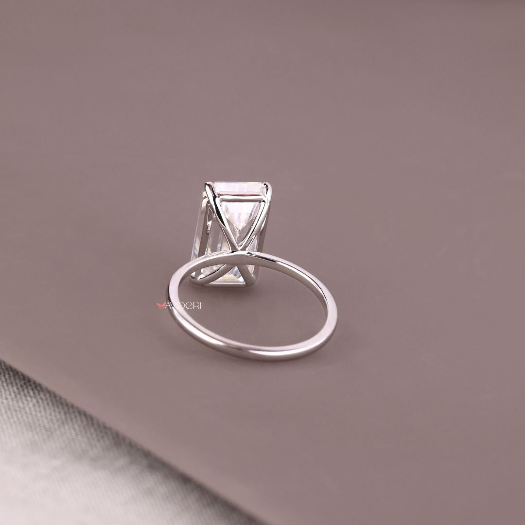 White gold solitaire ring featuring a brilliant emerald cut stone.