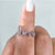 A white gold love ring shines under soft lighting.
 A white gold love ring shines under soft lighting.
