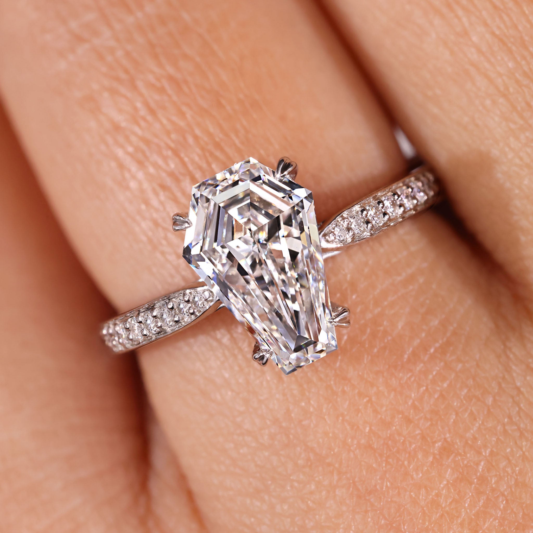 Coffin engagement ring with round cut diamond in pave setting.