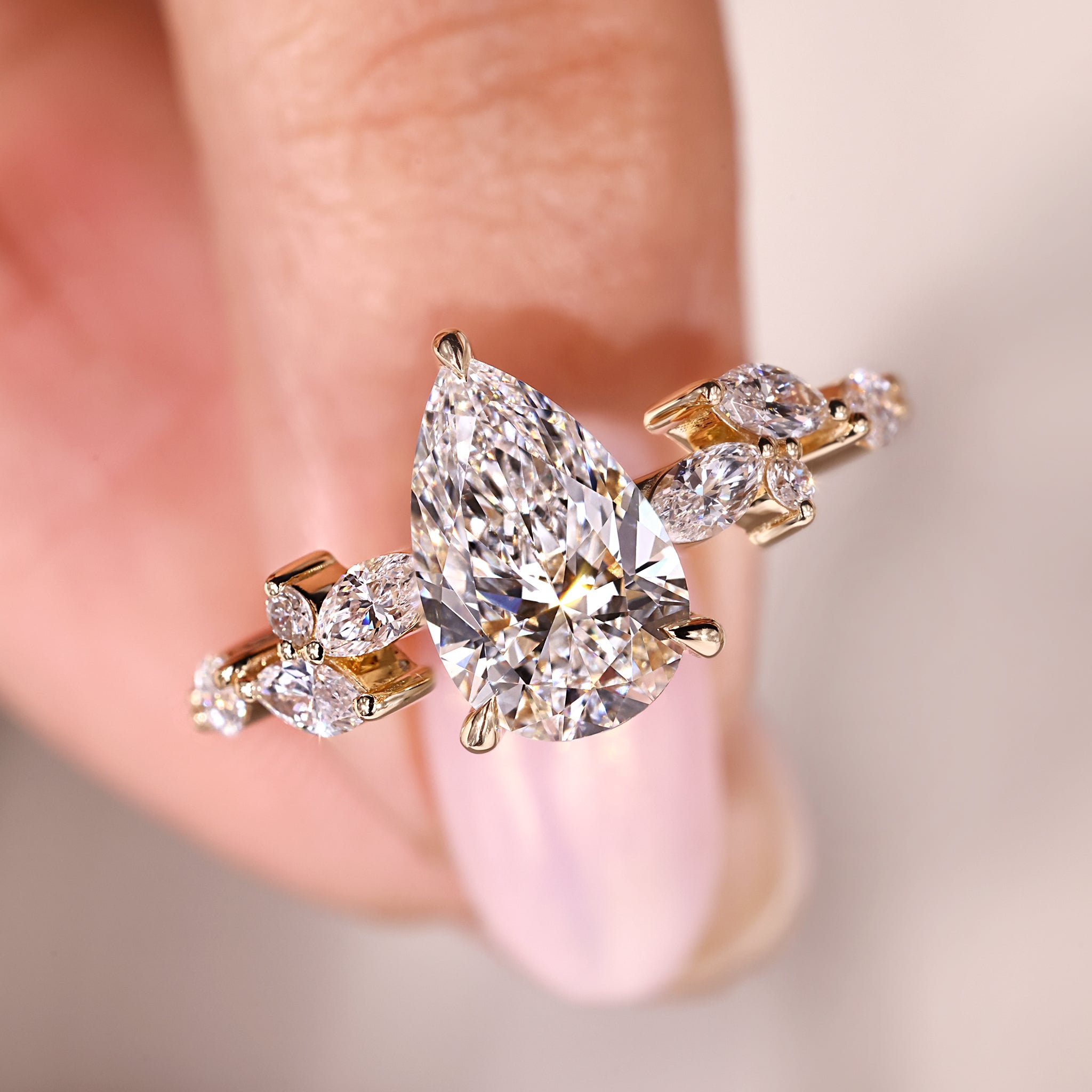 Pear diamond ring with a marquise and round side diamond layout in yellow gold.