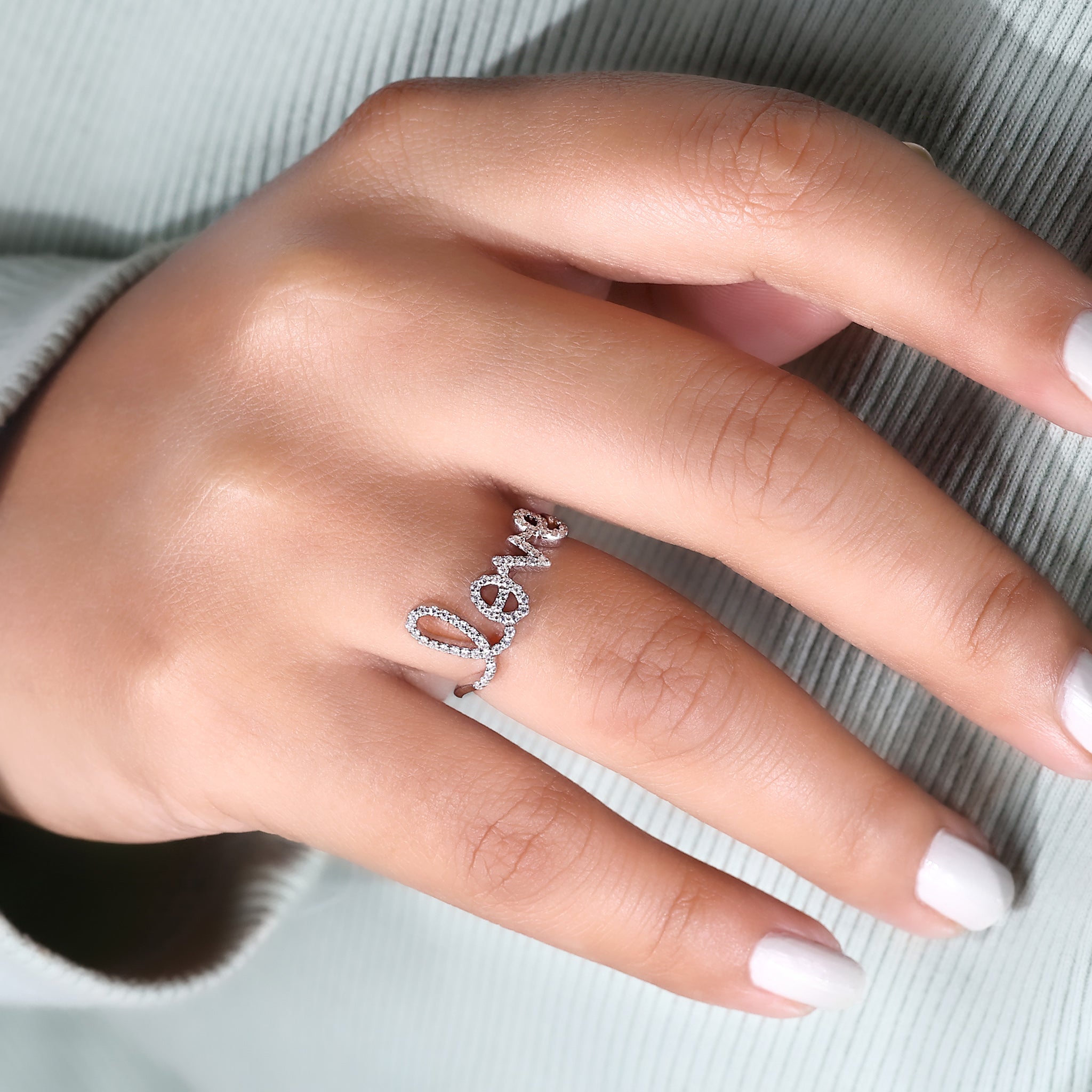 This love letter ring is worn on a delicate hand.