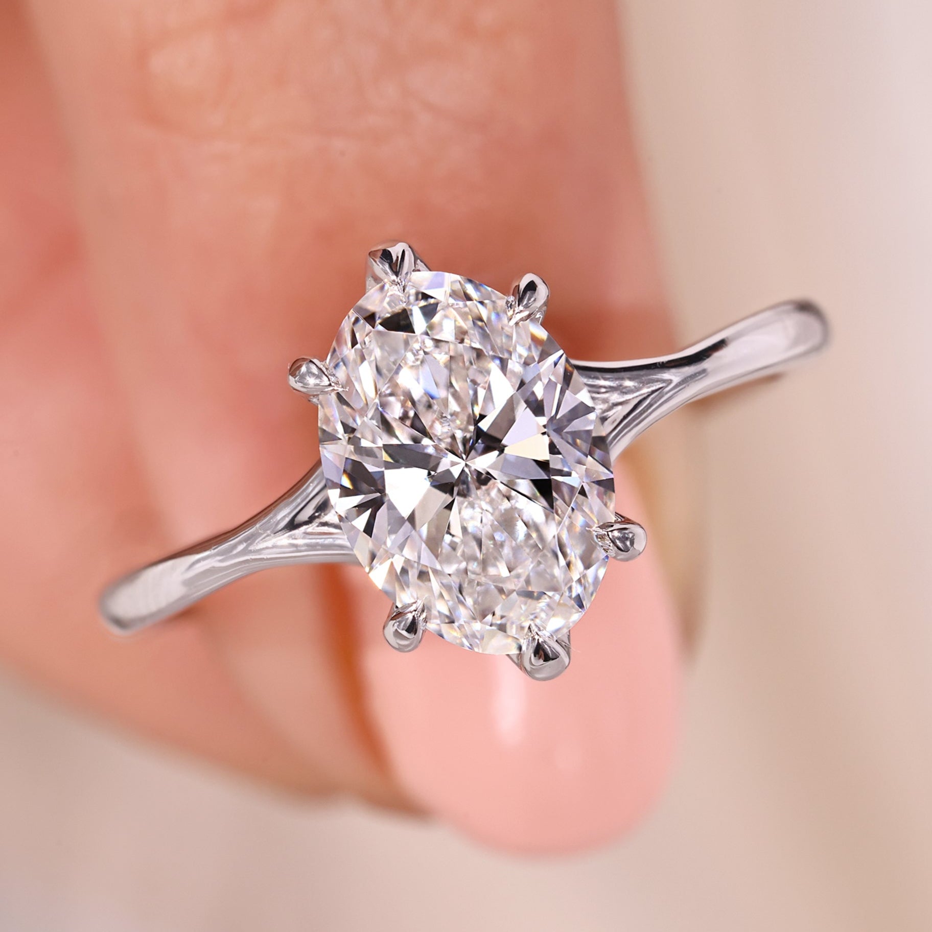 Solitaire oval diamond engagement ring with six claw prong in white gold.
