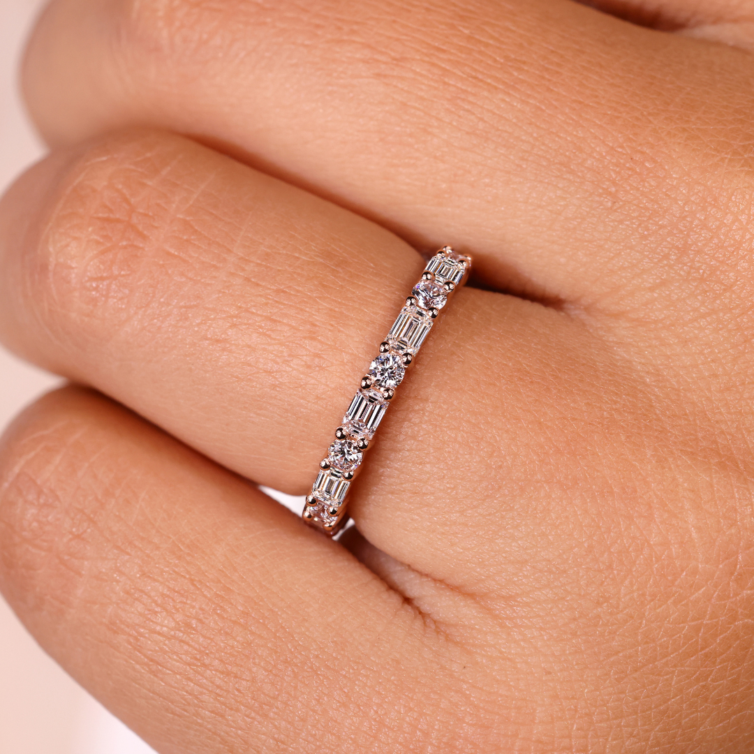 Emerald and round eternity band featuring sparkling diamonds.