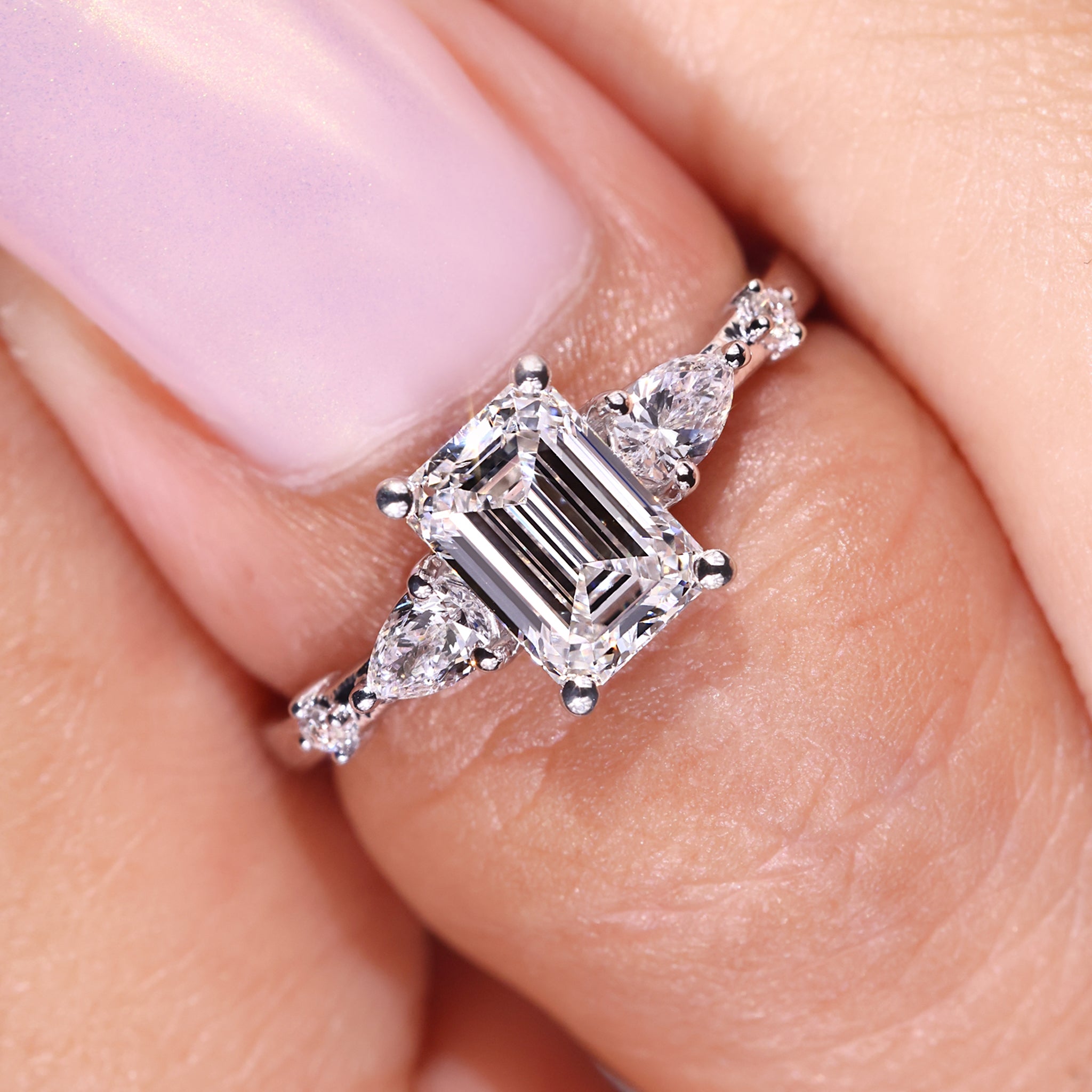 Emerald diamond engagement ring crafted with 2 pear side diamond ring in white gold ring.