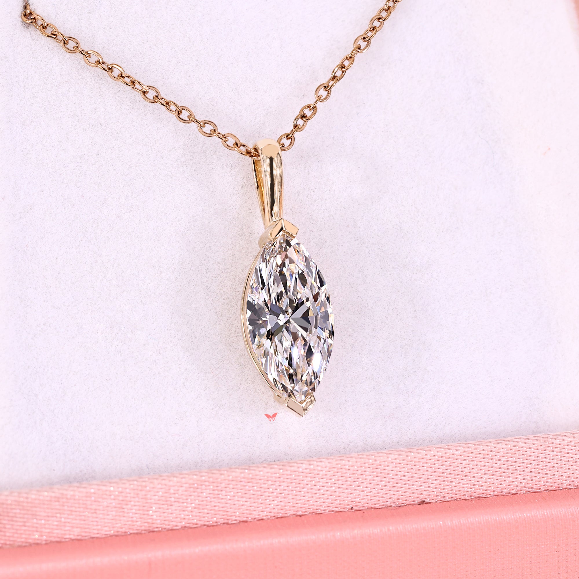 Gold necklace with a clear gemstone pendant on a pink surface