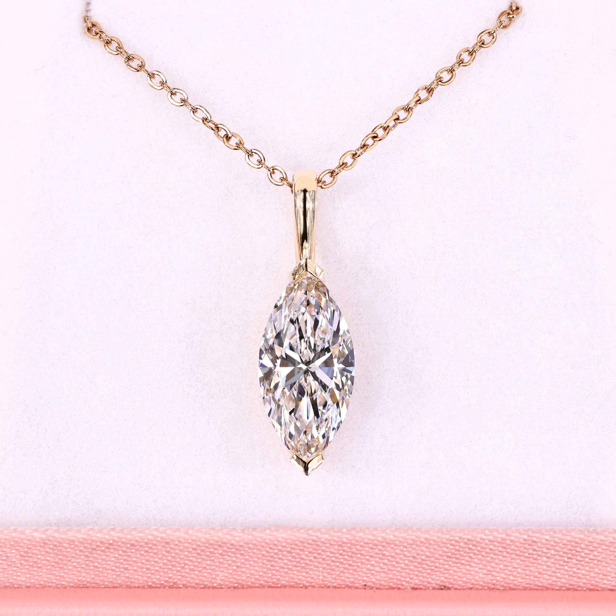 Diamond necklace with rose gold chain on a pink background