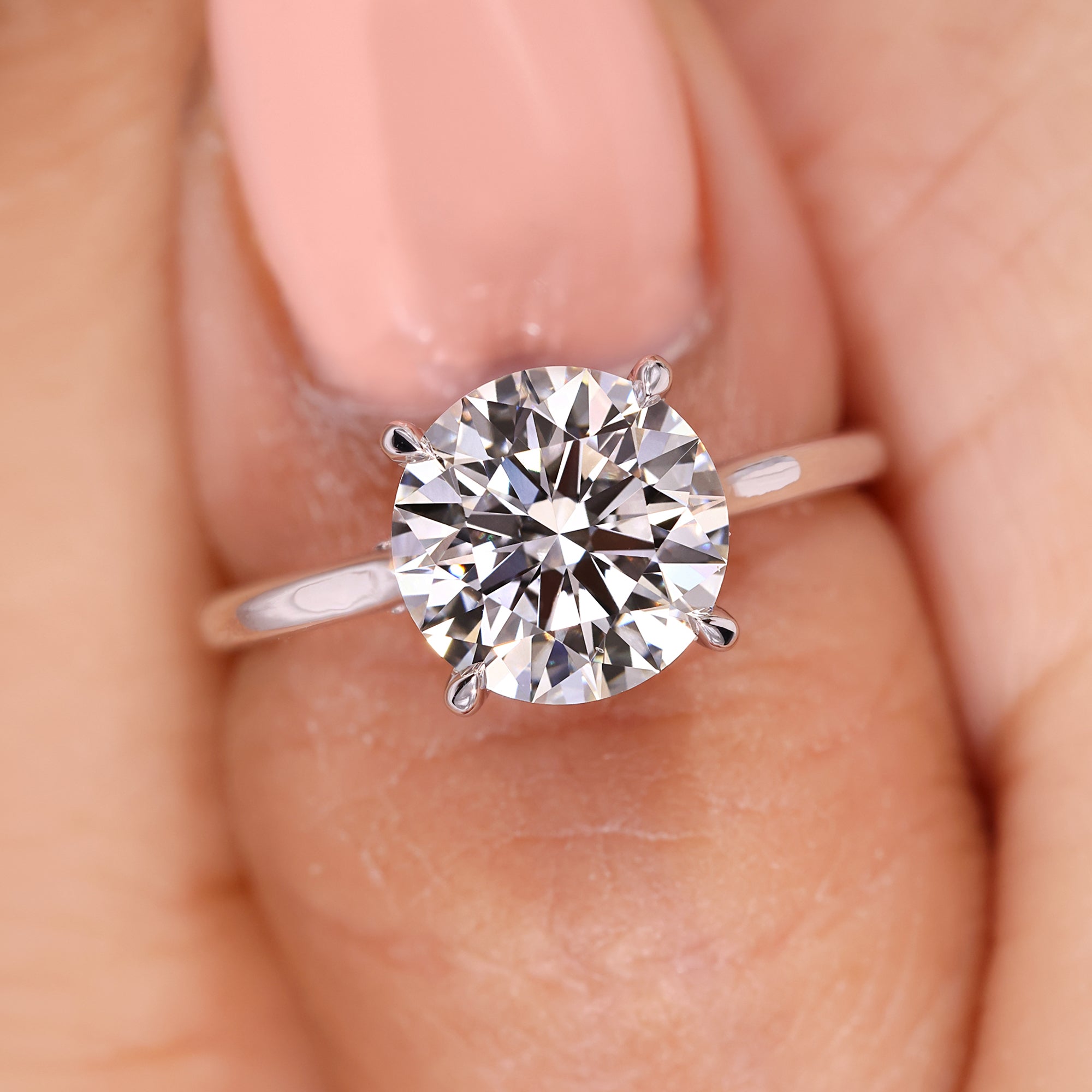 Round diamond ring with four prong setting and bridge accent.