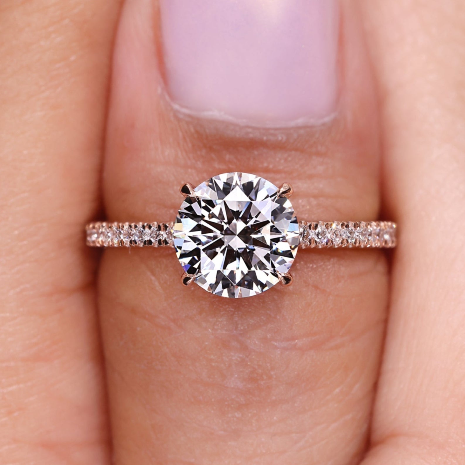 Round diamond engagement ring featuring a round diamond pave band and four claw prong setting.