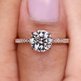 Round diamond engagement ring featuring a round diamond pave band and four claw prong setting.