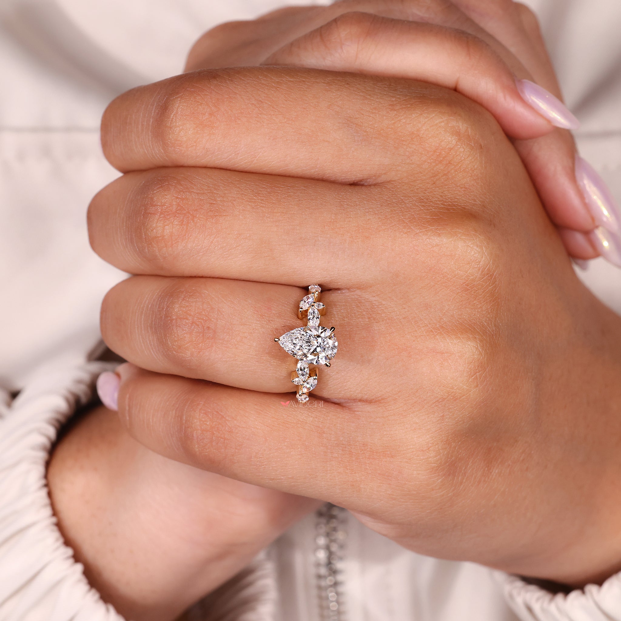 Three prong setting ring with a pear center and side stones in a secure design.