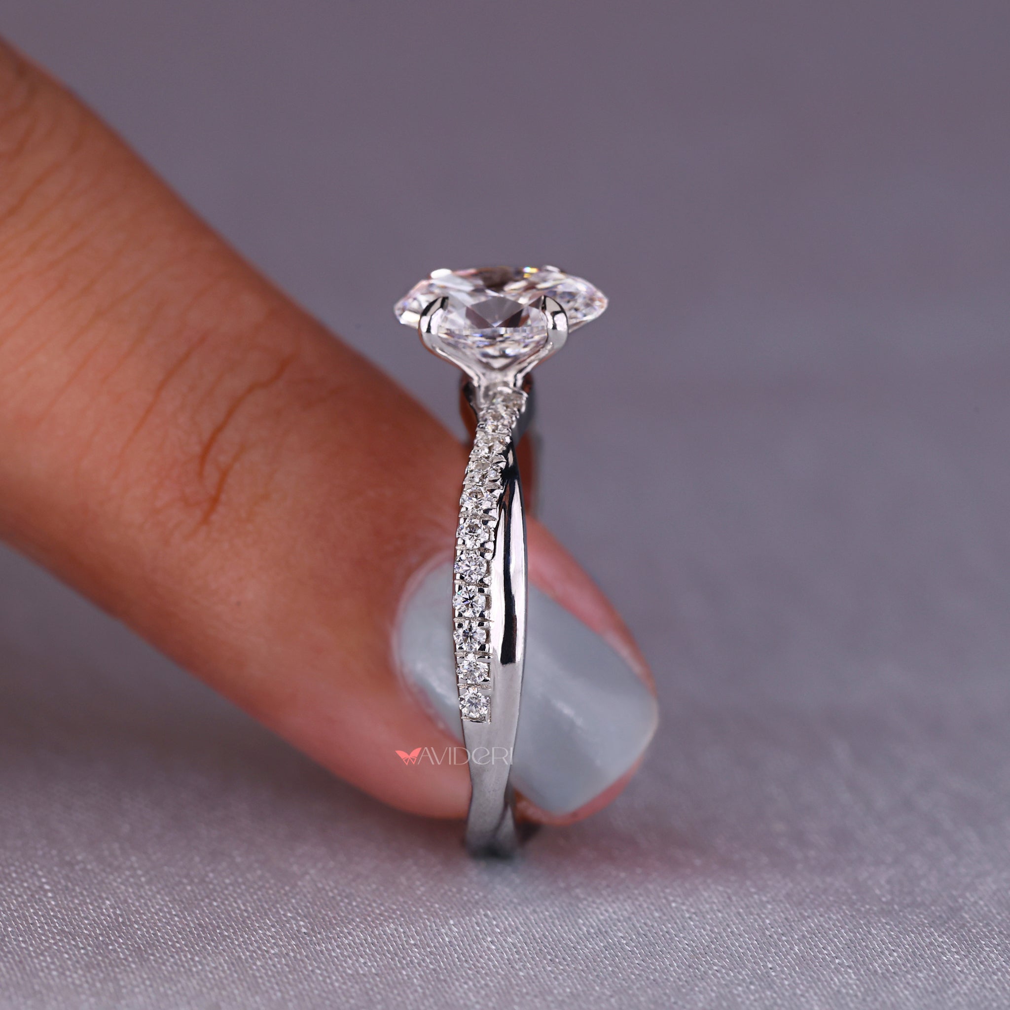 Twisted engagement ring crafted with handmade jewelry techniques and featuring an oval diamond with a pave setting.