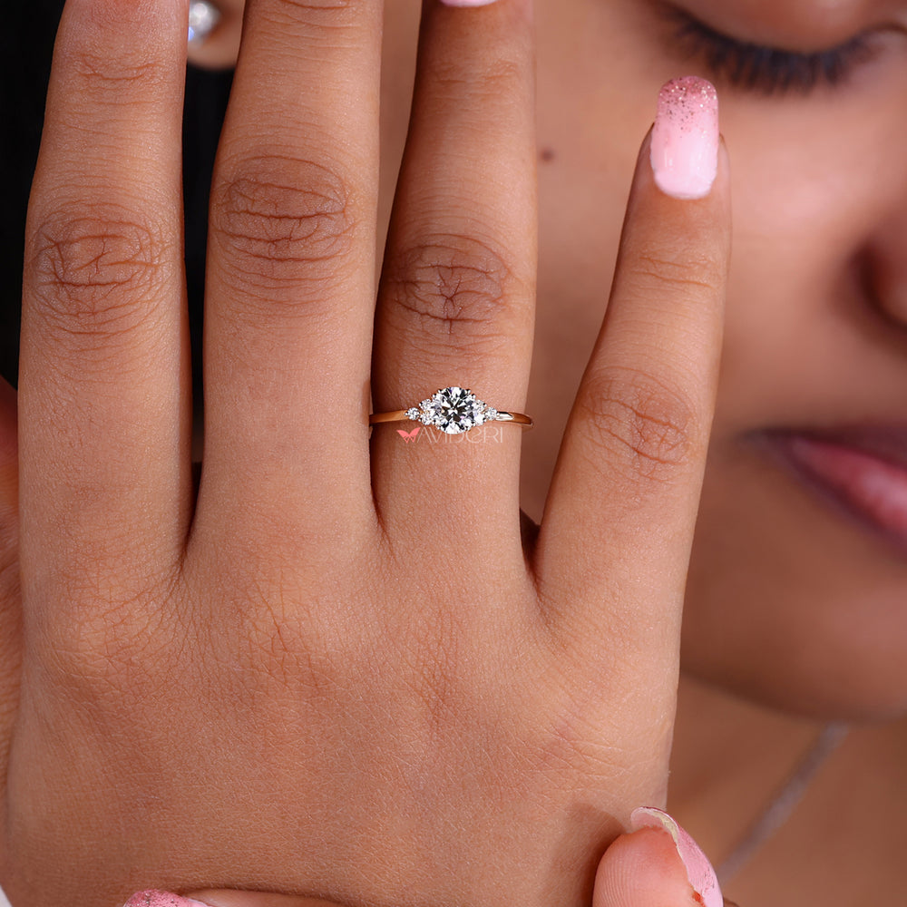 An Image of a hand wearing a delicate lab-grown diamond engagement ring with a round center stone and muse setting.