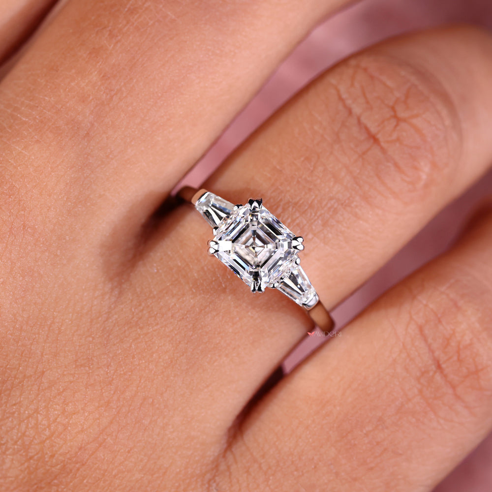 An Image of a hand wearing an Asscher cut diamond three stone engagement ring design for a classic appeal.