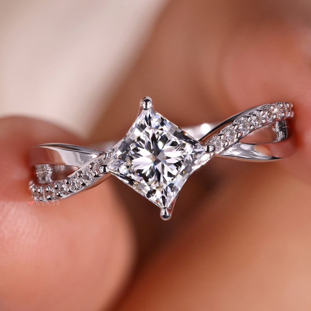Princess cut diamond ring with pave diamond band in elegant twist design.
