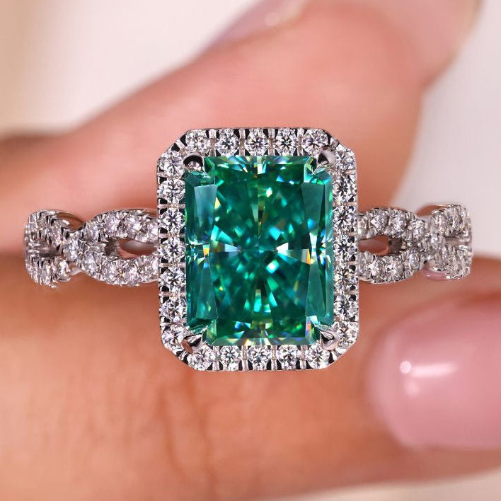 Radiant cut engagement ring with a dazzling cyan blue moissanite stone.
