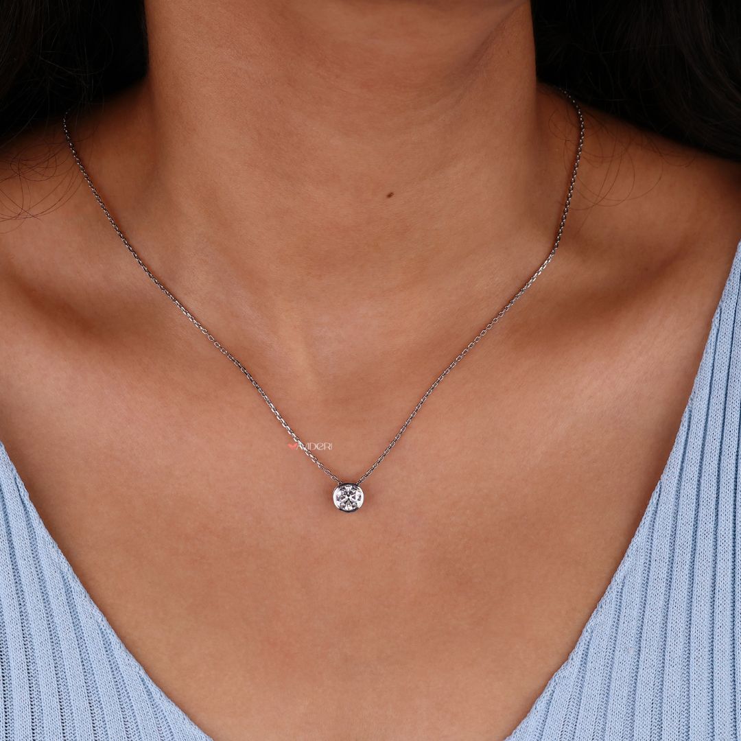 Solitaire pendant with a round moissanite stone in a bezel setting.
