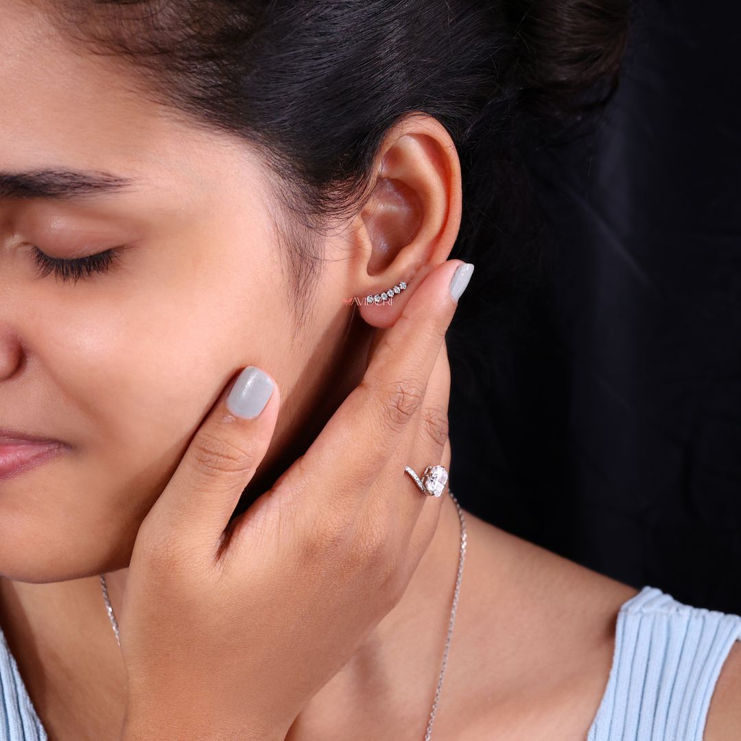 Diamond crawler stud earrings elegantly styled on a jewelry holder.
