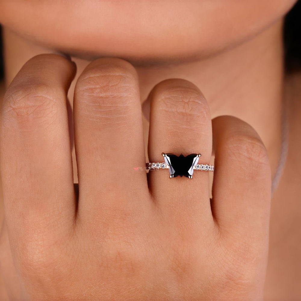 Round cut engagement ring with a black butterfly design for added elegance.
