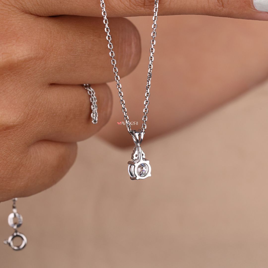 Charm pendant featuring a round cut moissanite stone.

