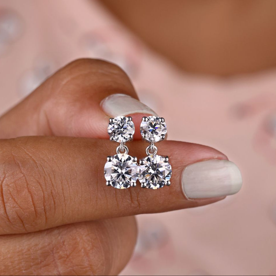 Round Cut Moissanite drop earrings in white gold with prong settings.
