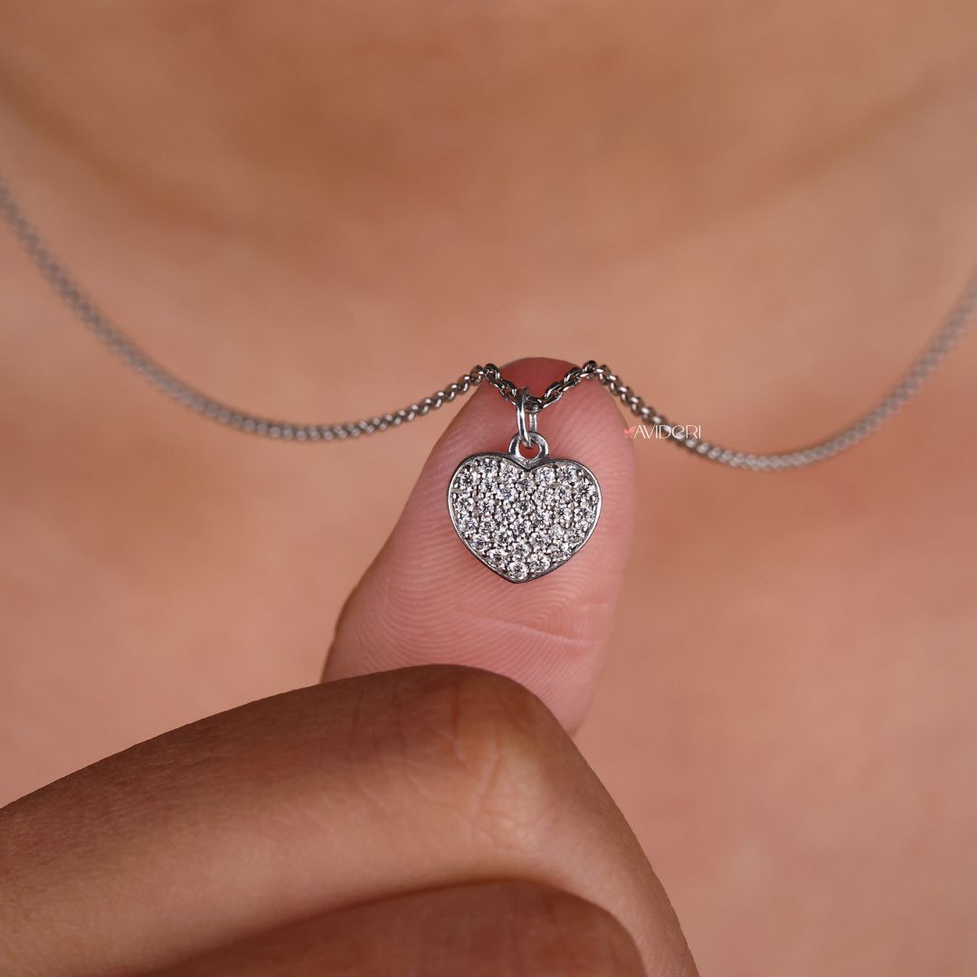 White gold pendant with a heart shape design and round moissanite stone.
