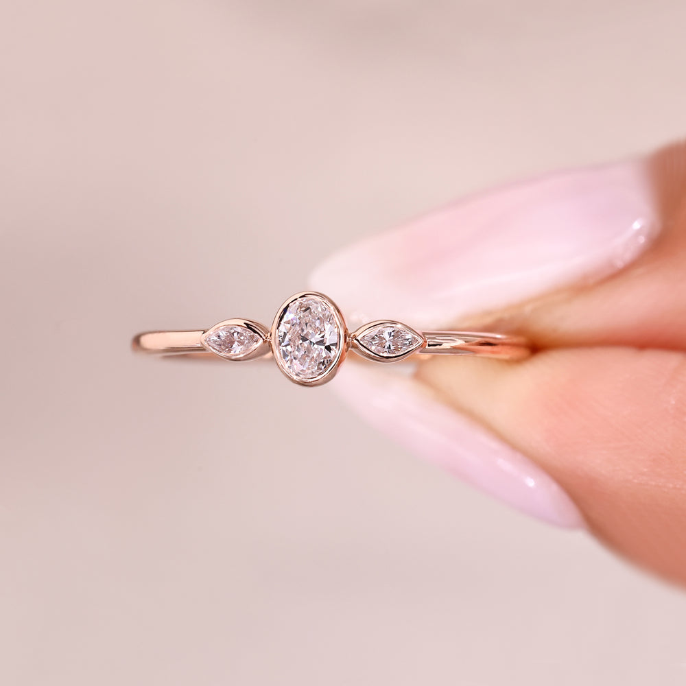 Three stone ring featuring bezel set oval center diamond.
