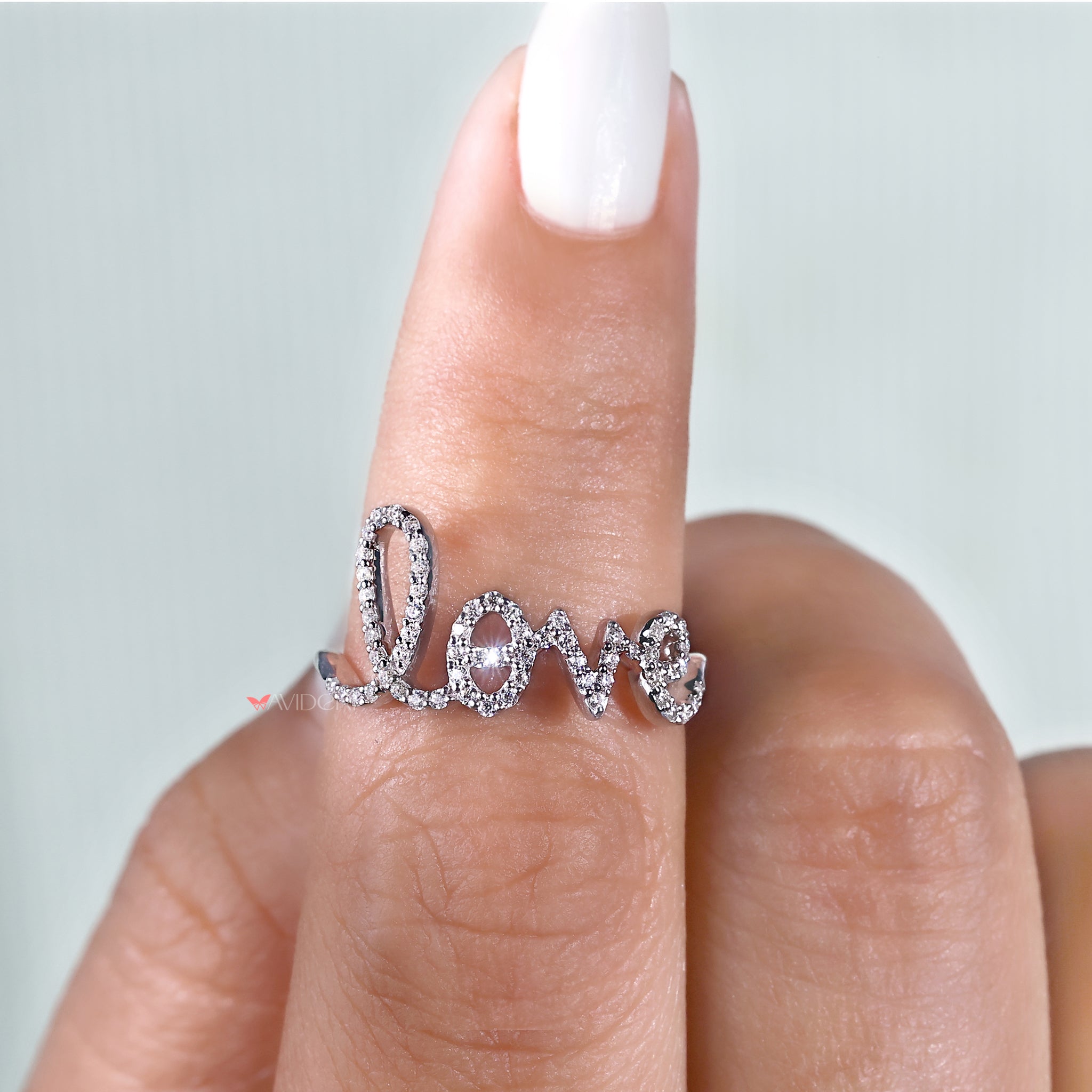 A white gold love ring shines under soft lighting.
