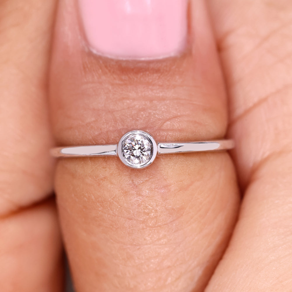 Minimalist round diamond ring with smooth bezel design.
