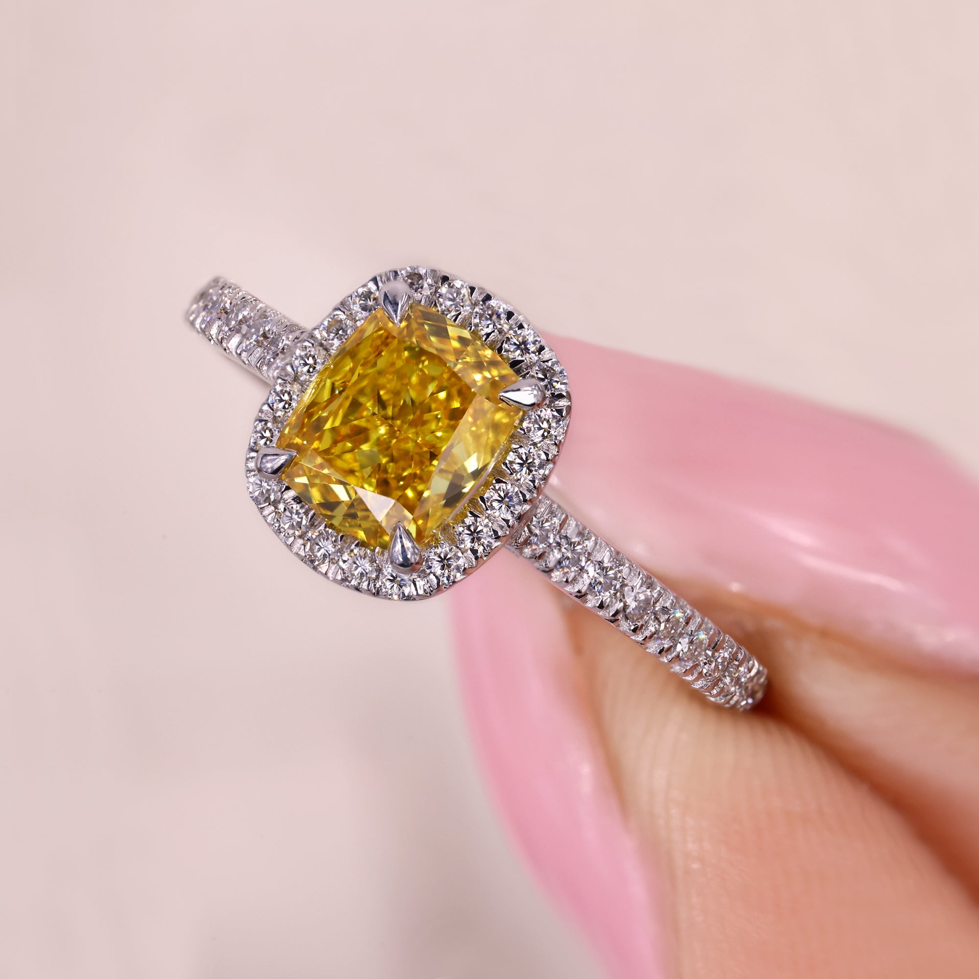 Cushion cut yellow diamond ring with halo and pave style.
