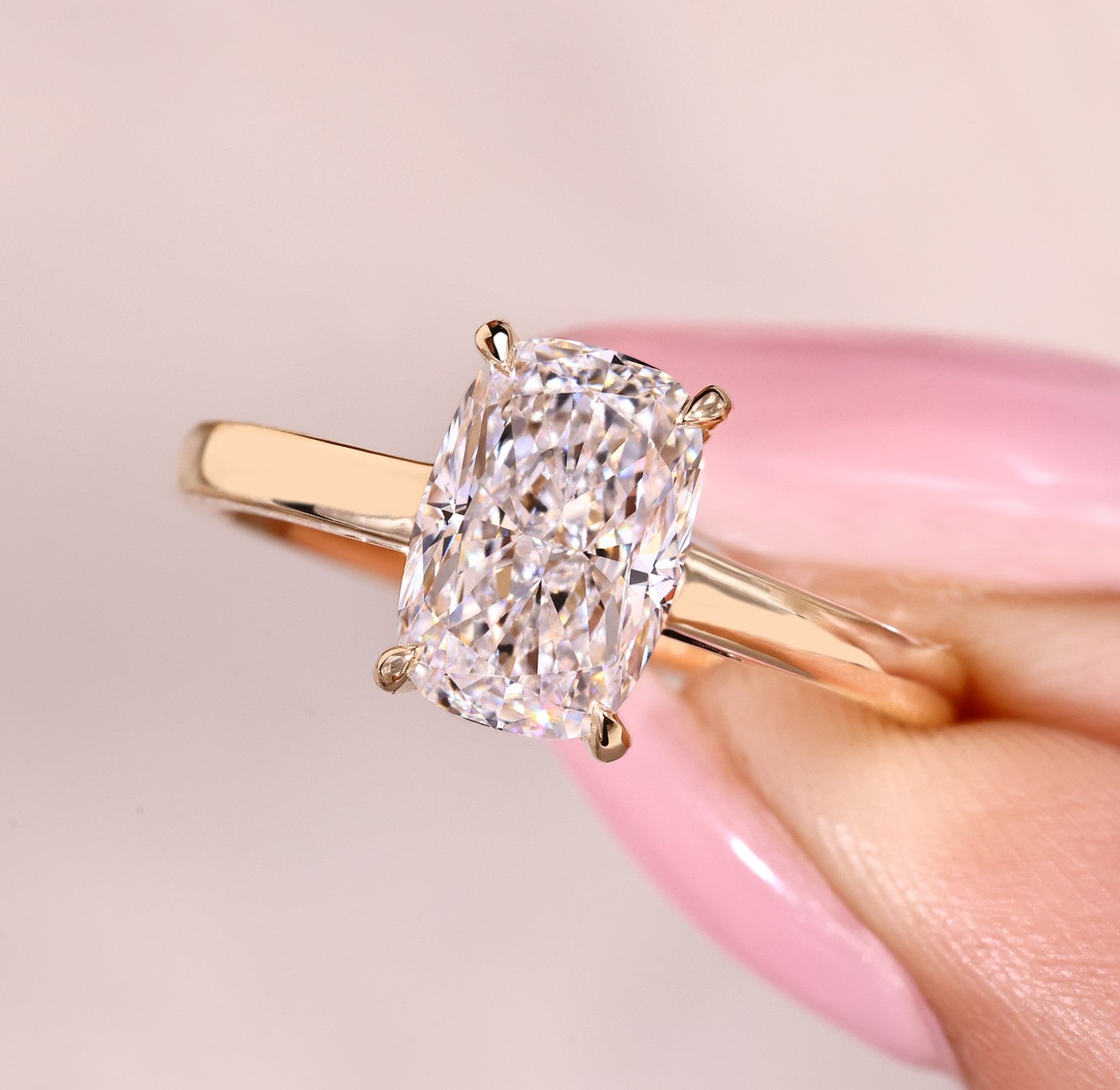 Cushion cut diamond ring with solitaire cathedral setting.