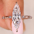 Elongated marquise engagement ring with distant pave diamond accents
