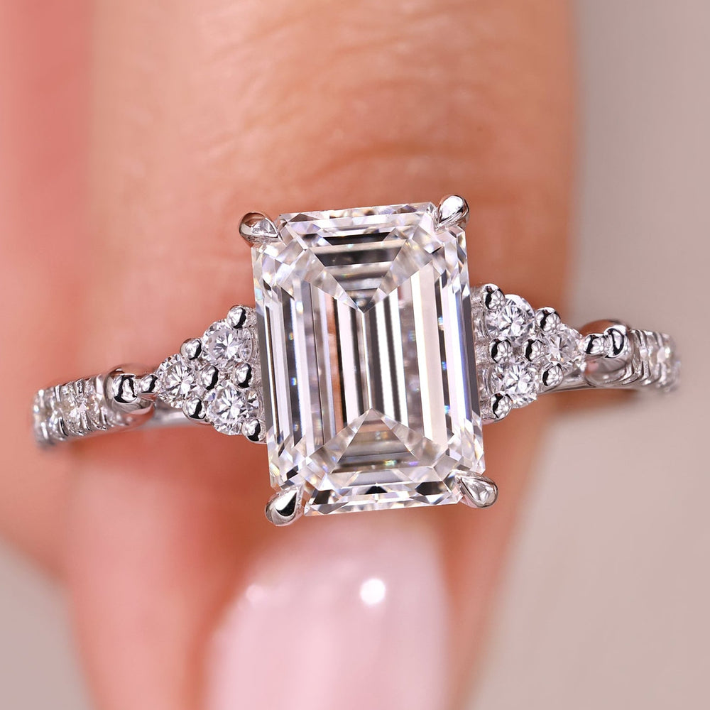 Emerald cut diamond engagement ring with pave band.
