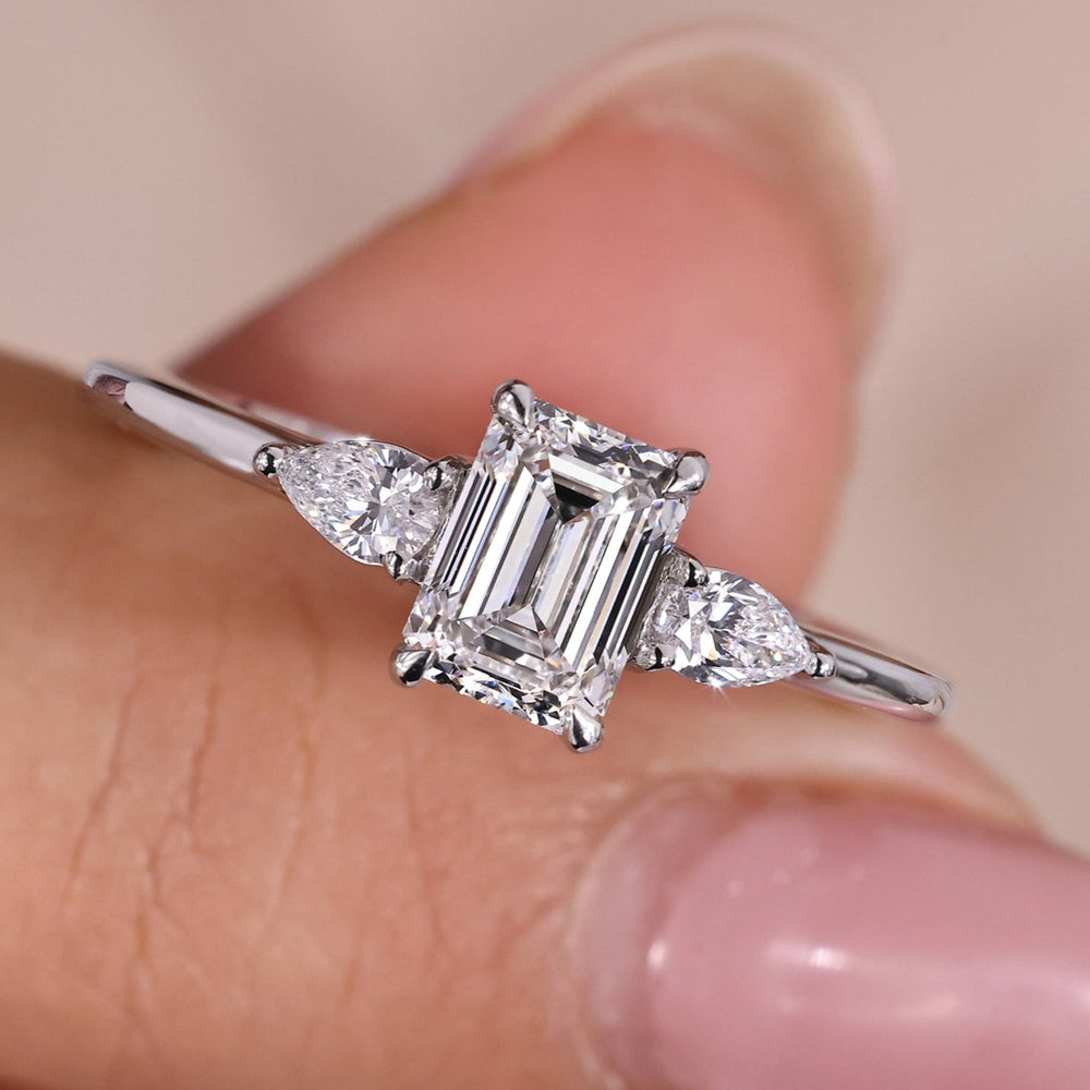 Emerald cut diamond engagement ring featuring 2 pear side stones, offering timeless elegance with a modern twist.
