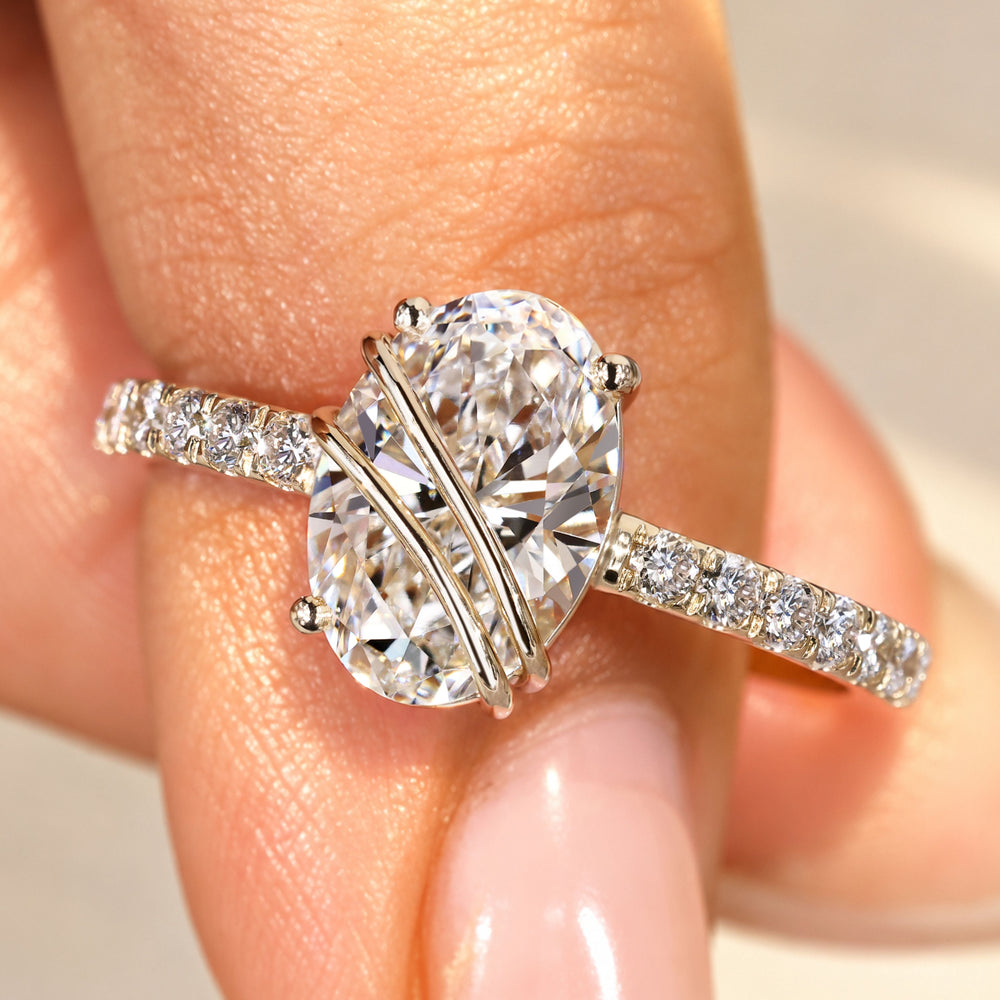 Oval diamond engagement ring with round diamond pave.
