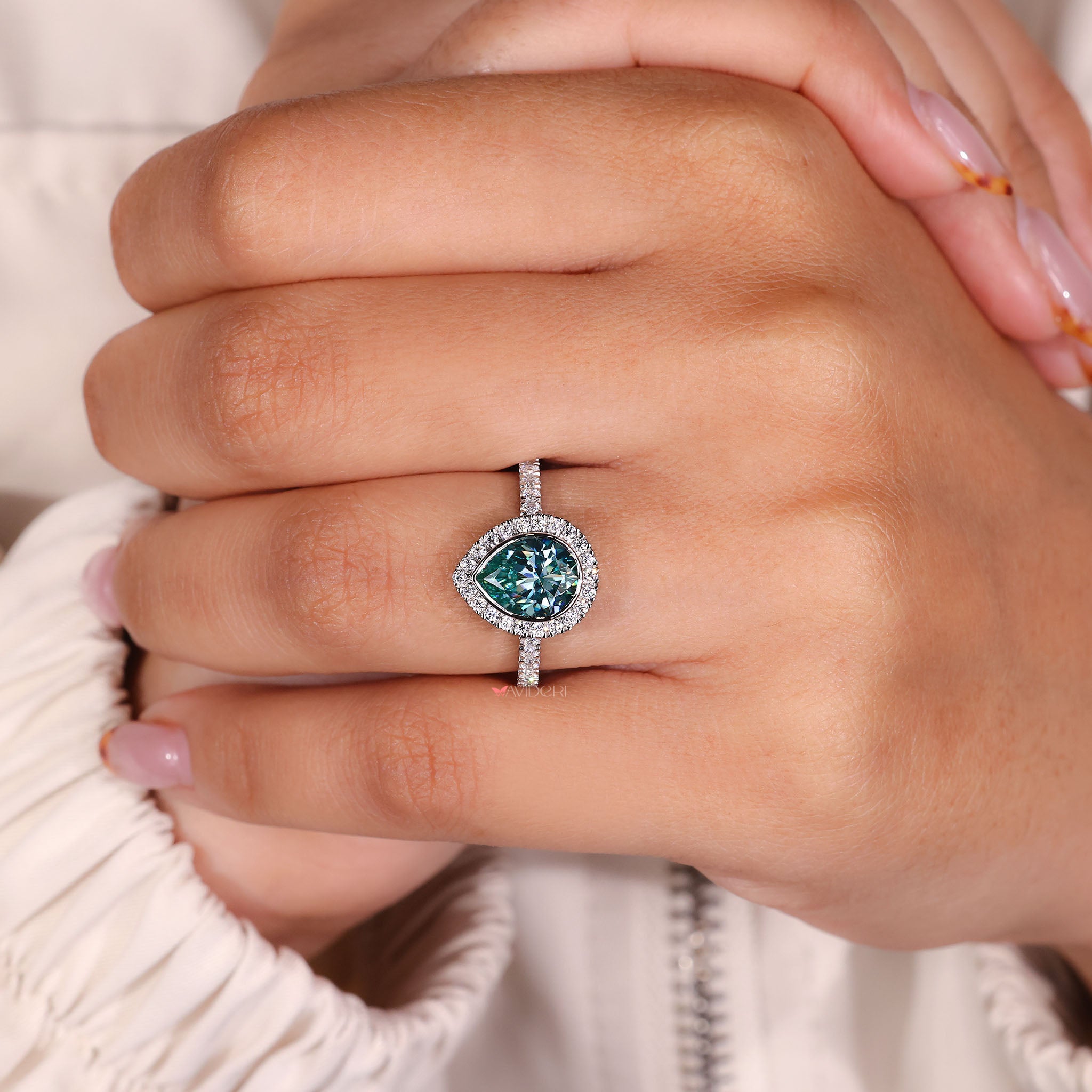 Halo setting ring featuring a gold pear cut center stone.