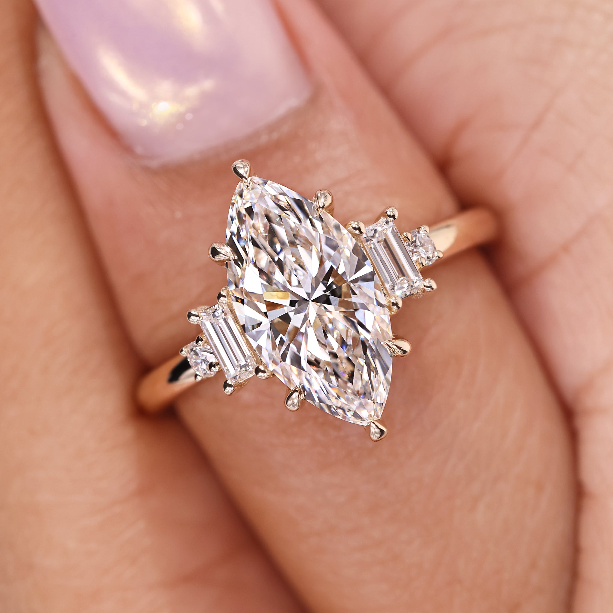 Marquise diamond engagement ring crafted with baguette and round side stones in yellow gold.
