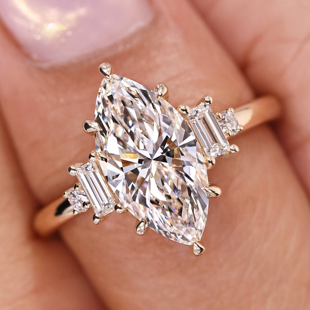 Marquise diamond engagement ring crafted with baguette and round side stones in yellow gold.
