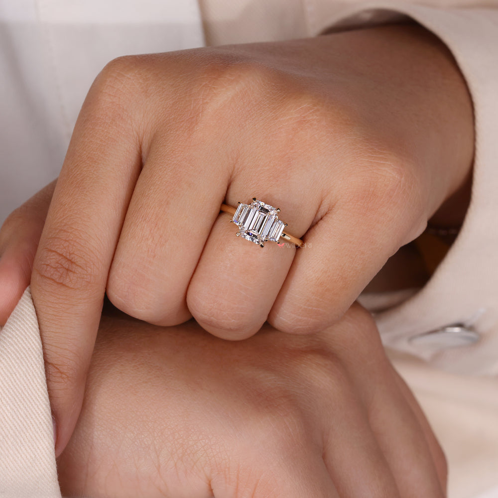 Three stone wedding ring with an emerald cut diamond for timeless elegance.
