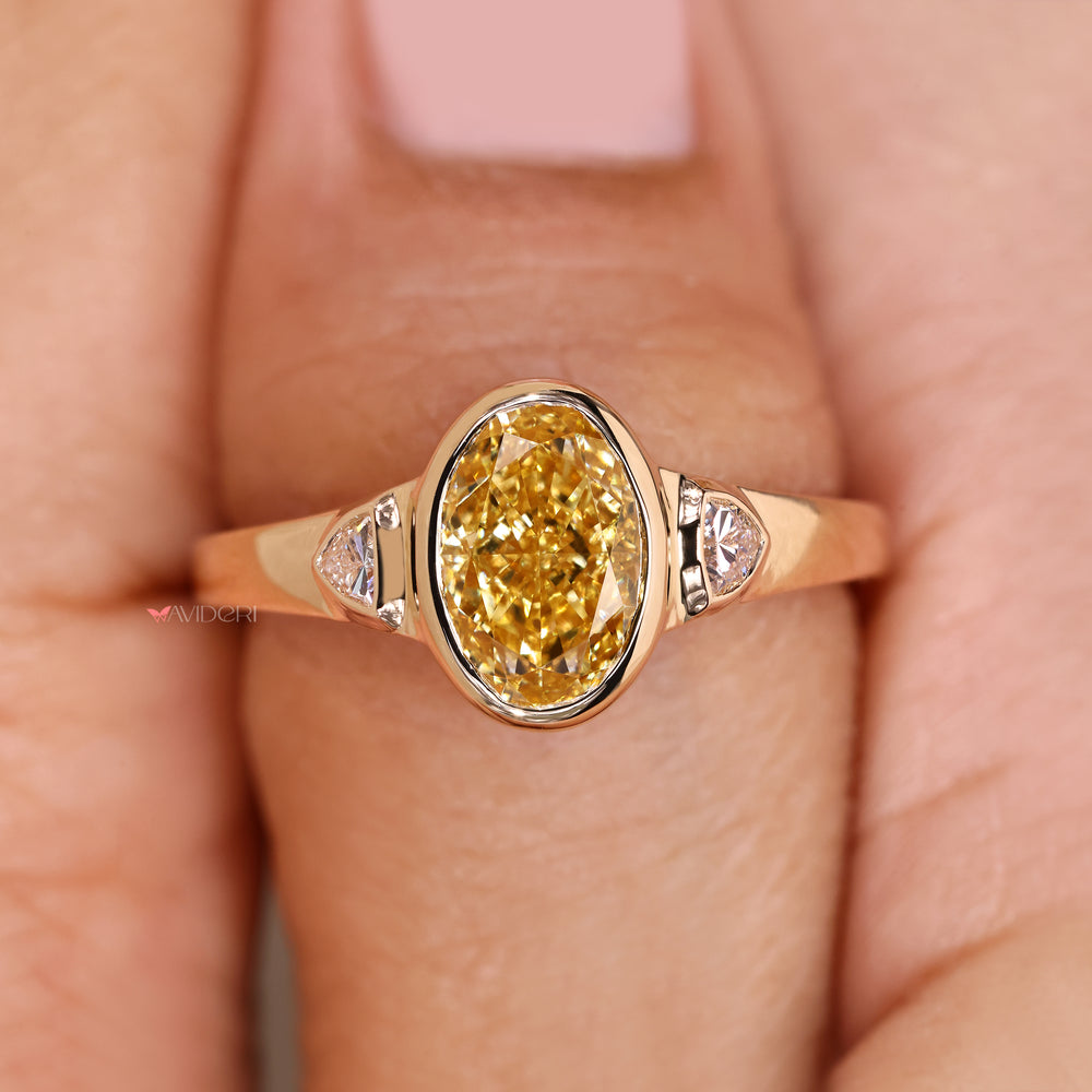 Oval cut ring with yellow diamond and sides.
