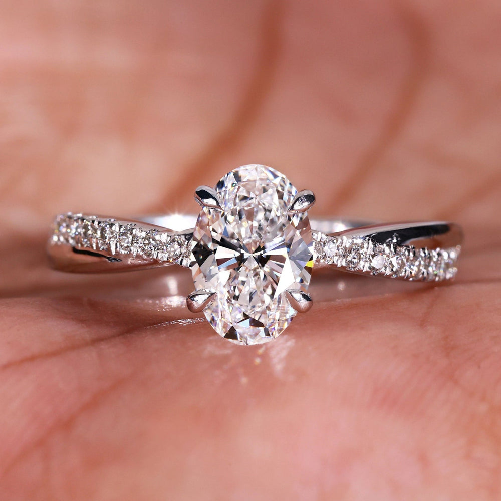 Twisted engagement ring with an oval cut diamond and pave diamond ring design for a modern and elegant look.

