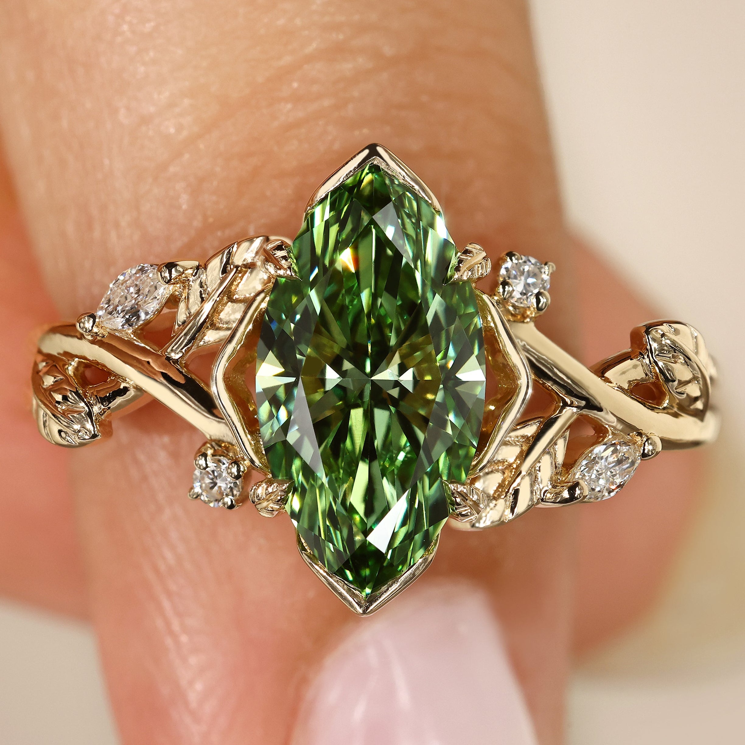 Green marquise diamond engagement ring with leaf detail.
