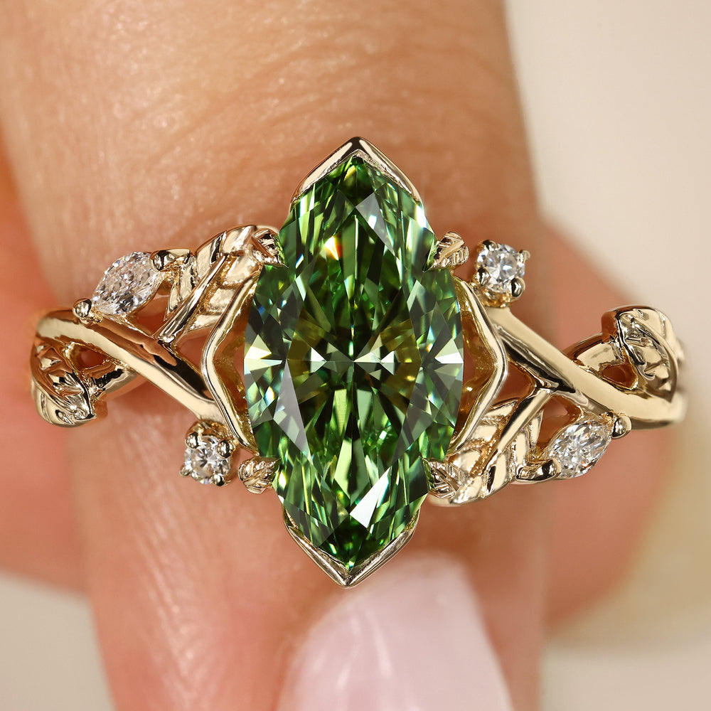 Green marquise diamond engagement ring with leaf detail.
