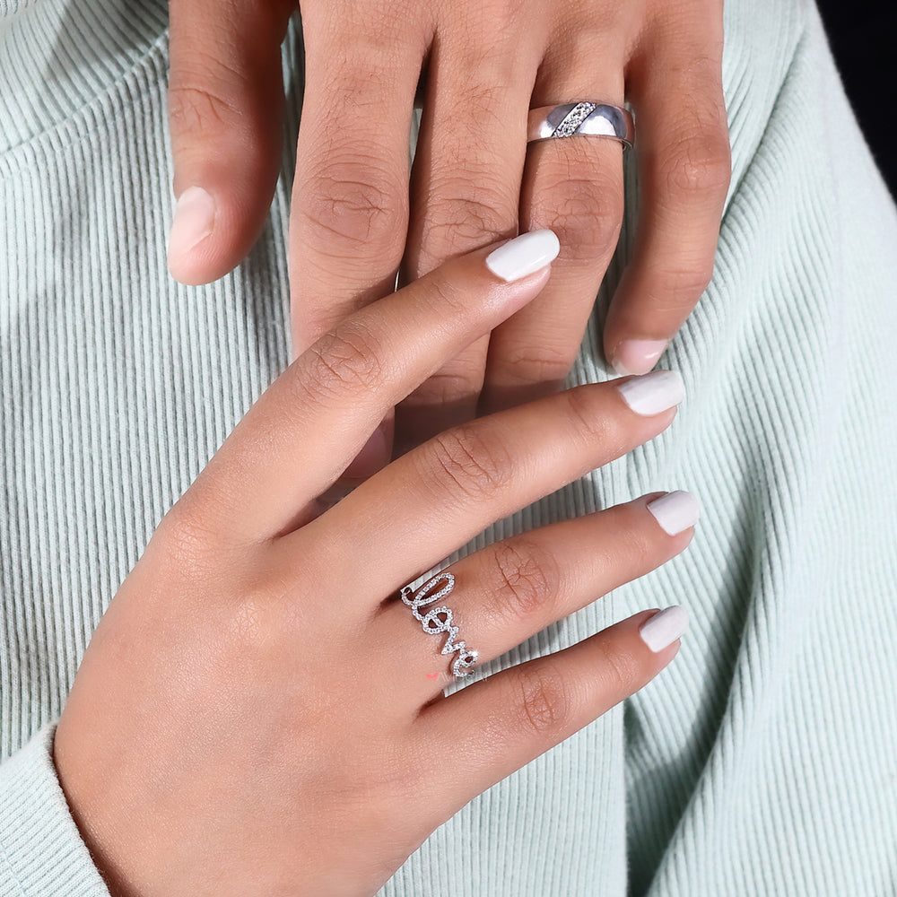 This white gold ring rests on a textured display stand.
