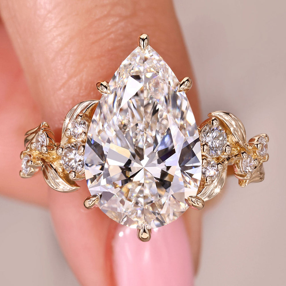 Pear cut diamond ring with round side stone cluster setting.
