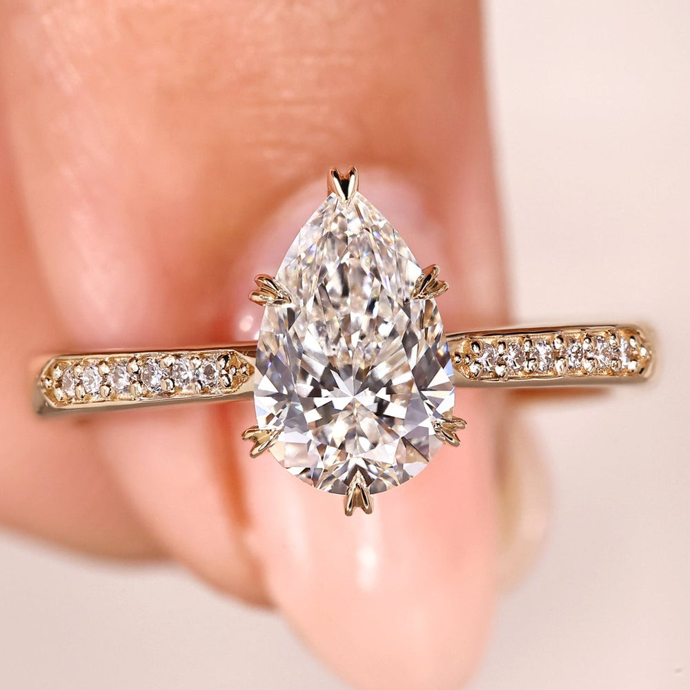 Pear cut diamond ring with pave band and cathedral setting.
