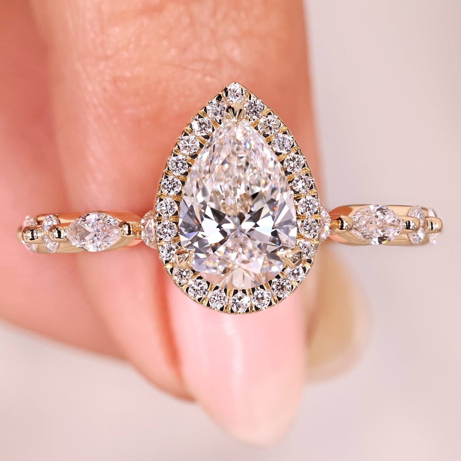 Pear diamond ring with halo and pave band.
