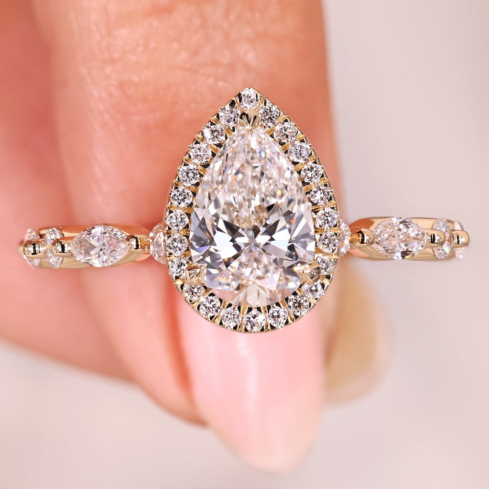 Pear diamond ring with halo and pave band.
