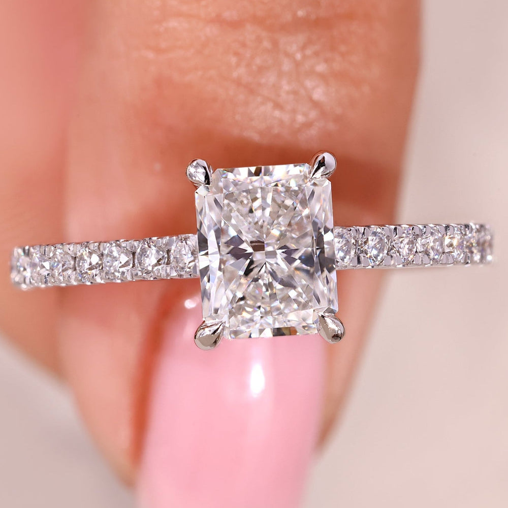 Radiant cut diamond ring with pave band and cathedral setting.