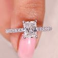 Radiant cut diamond ring with pave band and cathedral setting.